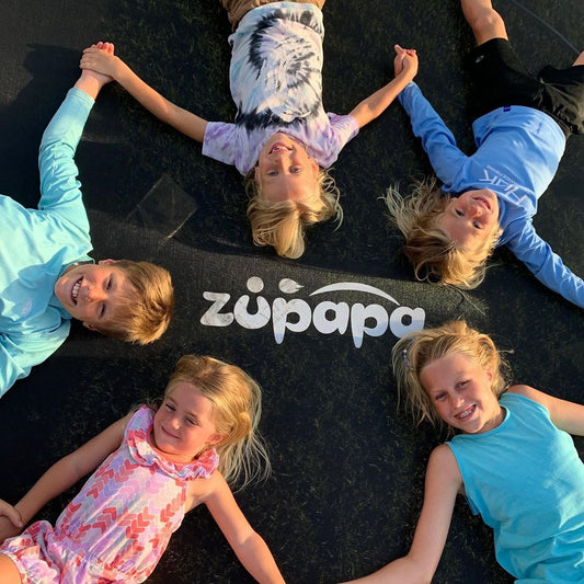 5 kids lying on a Zupapa outdoor trampoline, smiling