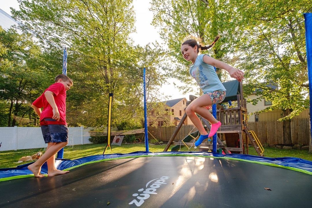 2021 spring bounce time - kids are jumping on a Zupapa outdoor trampoline in a sunny day. 